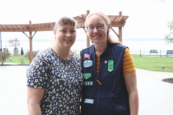 two adult volunteers smiling at an outdoor event