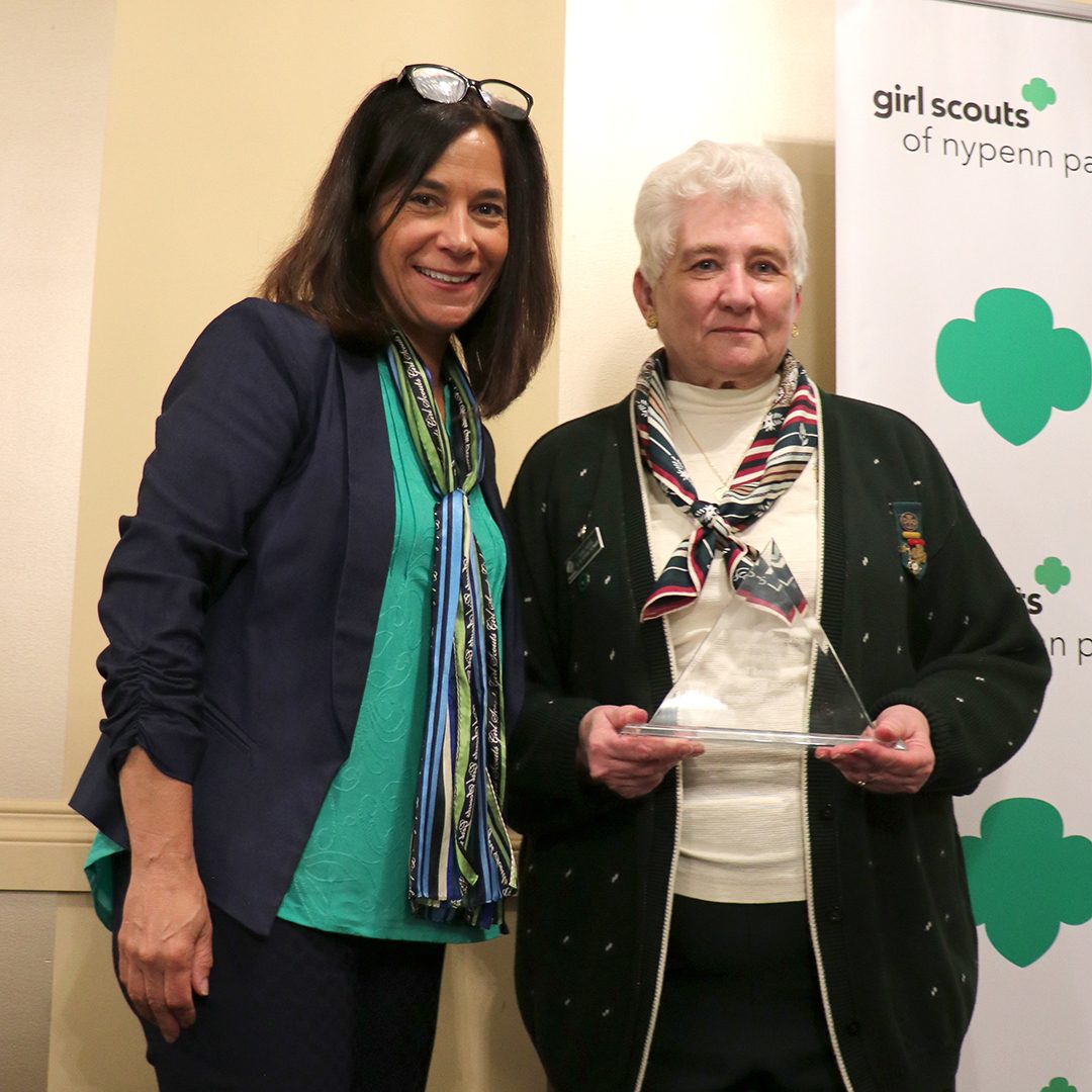 photo of diane bootie and grace nassar, diane is holding the hall of fame trophy, a glass triangle shape